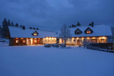 a large house with lights on in the snow at Alpine Homestead in Goreljek