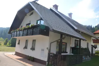 a white house with a balcony with flowers on it at Apartments Kot'č in Kranjska Gora