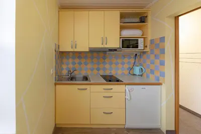 a small kitchen with yellow cabinets and a white refrigerator at Apartments Kot'č in Kranjska Gora