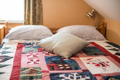 a bed with two pillows and a quilt on it at Holiday Home Mirt with HotTub & Sauna in Blanca