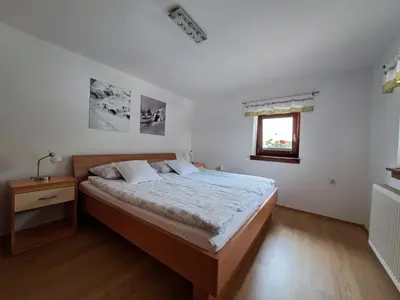 a bedroom with a large bed and a window at Apartments Pr'Krštano in Kranjska Gora