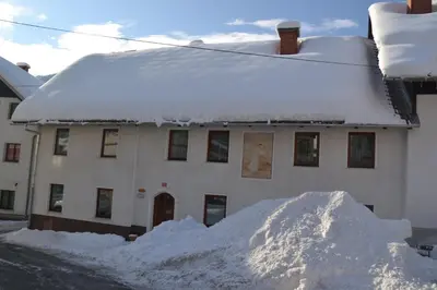 a pile of snow in front of a house at Apartments Pr'Krštano in Kranjska Gora