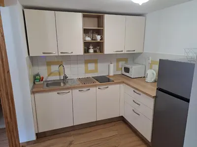 a kitchen with white cabinets and a sink and a refrigerator at Apartments Pr'Krštano in Kranjska Gora