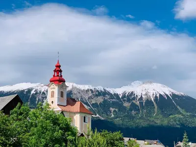 a church with a snow covered mountain in the background at STATUS Apartments in Bled