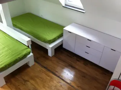 a room with two beds and a desk with a green mattress at Apartments Podkoren 82 in Kranjska Gora