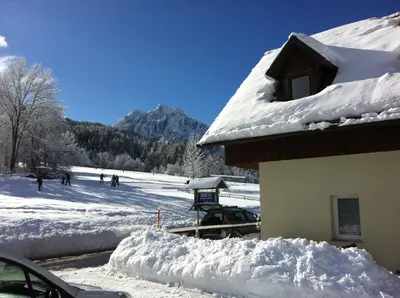 a snow covered roof of a house with people on a ski slope at Apartments Podkoren 82 in Kranjska Gora
