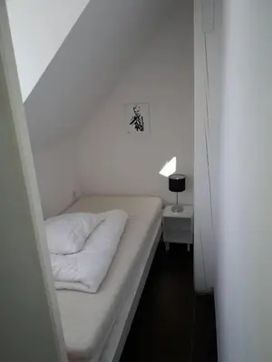 a small white room with a bed and a lamp at Apartments Podkoren 82 in Kranjska Gora