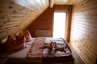 a bed in a wooden room with two dolls on it at Korošec Apartments and Wellness Centre in Mozirje