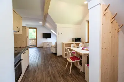 a kitchen and living room with a table and chairs at Bohinj Apartments Goldhorn Kingdom in Bohinj