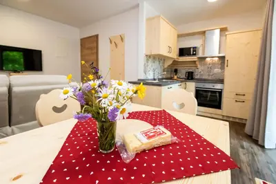 a table with a vase of flowers on a red napkin at Bohinj Apartments Goldhorn Kingdom in Bohinj