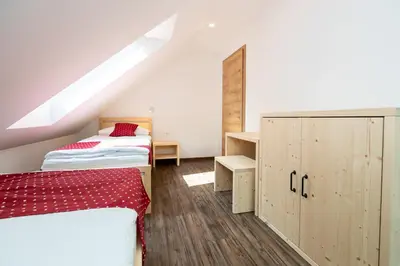 a attic bedroom with two beds and a cabinet at Bohinj Apartments Goldhorn Kingdom in Bohinj