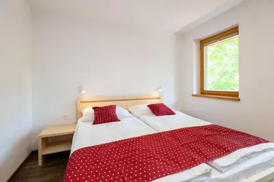 a bedroom with a red and white bed with a window at Bohinj Apartments Goldhorn Kingdom in Bohinj
