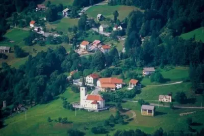 a small village on a green hill with houses at Apartments Pri Marjetki in Cerkno