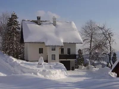 a house covered in snow in front at Apartments Pri Marjetki in Cerkno