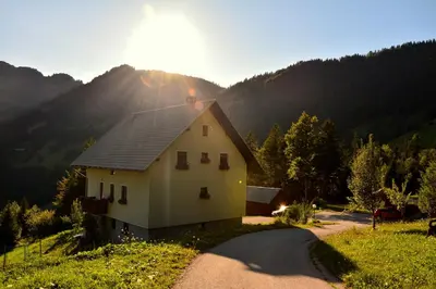 a small white house on a hill with a road at Apartments Pri Marjetki in Cerkno