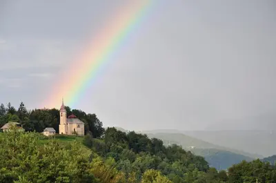 a rainbow over a church on top of a hill at Guesthouse Dolinsek in Sevnica