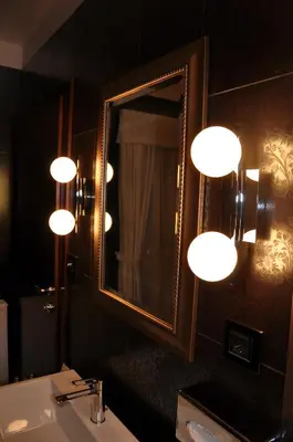 a bathroom with a mirror and a sink and lights at Guesthouse Dolinsek in Sevnica