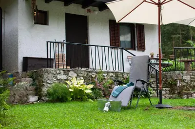 a chair and an umbrella in front of a house at NATURALINA HOLIDAY HOUSE in Tribussa Superiore