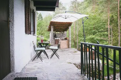 a patio with two chairs and an umbrella at NATURALINA HOLIDAY HOUSE in Tribussa Superiore
