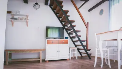 a living room with a staircase and a tv at NATURALINA HOLIDAY HOUSE in Tribussa Superiore