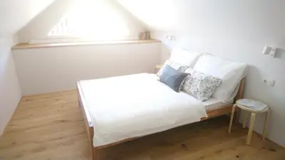 a small white bed with pillows and a window at Apartments Alteri Domi in Bohinj