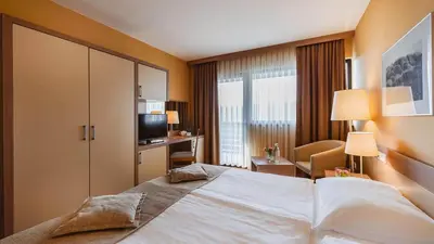 a hotel room with a large bed and a desk at Terme Olimia - Hotel Breza in Podčetrtek