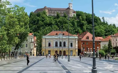 a group of people walking and riding bikes on a city street at Royal Vega Apartment in Ljubljana
