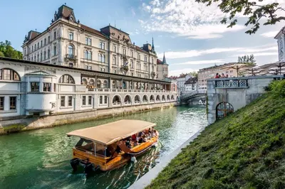 a boat in a river in front of a building at Royal Vega Apartment in Ljubljana
