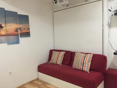 a red couch sitting in a room with paintings at Apartment Red Square in Ljubljana