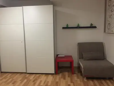 a living room with a chair and a red stool at Apartment Red Square in Ljubljana
