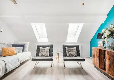 a bedroom with two chairs and a bed with skylights at Blissful Loft Tivoli in Ljubljana