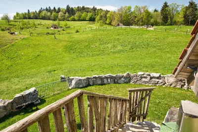 a wooden balcony with a view of a field at Farm Stay Ana in Višnja Gora