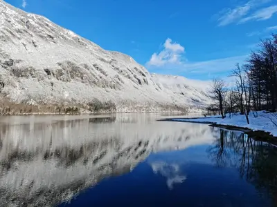 a snow covered mountain reflecting in a lake at River View Apartments Irena in Bohinj