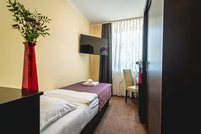 a hotel room with a bed and a vase with flowers at Casino & Hotel ADMIRAL Ptuj in Ptuj