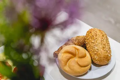 a plate with two pastries on a table with a flower at Casino & Hotel ADMIRAL Ptuj in Ptuj