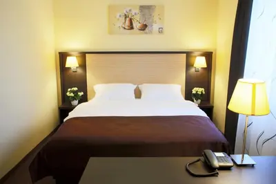 a bed in a hotel room with a phone on a desk at Casino & Hotel ADMIRAL Ptuj in Ptuj