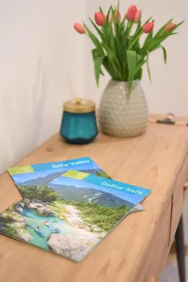 a book sitting on a wooden table with a vase of flowers at Apartment Bc in Bovec