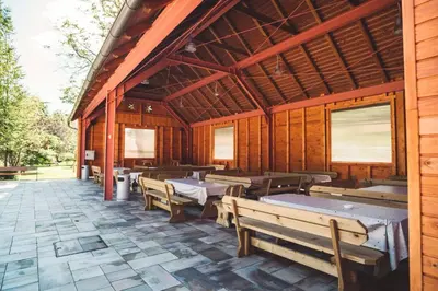 a wooden pavilion with tables and benches on a patio at Camp Podgrad Vransko in Vransko
