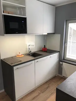 a kitchen with white cabinets and a sink and a window at Apartments ViTa in Kranjska Gora