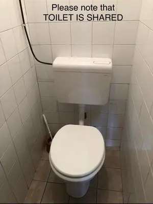 a white toilet in a bathroom with a sign on the wall at Castle View Studio in Ljubljana