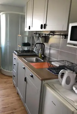 a kitchen with white cabinets and a sink and a microwave at Castle View Studio in Ljubljana