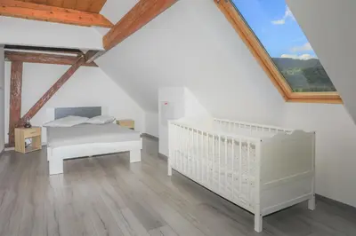 a bedroom with a crib and a bed in a attic at Apartment Krnicar in Zgornje Gorje