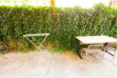 a table and chairs in front of a green hedge at Na Kopitarjevi in Laško