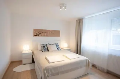 a white bedroom with a large bed with two lamps at Apartment Galerija Bled in Bled