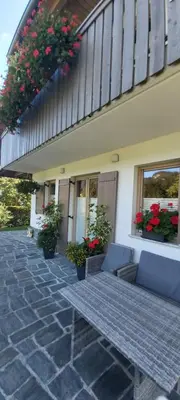 a patio with a couch and flowers on a building at Apartma LODI BOHINJ Za dve,štiri, šest, ali osem oseb in Bohinj