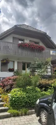 a house with a balcony with red flowers on it at Apartma LODI BOHINJ Za dve,štiri, šest, ali osem oseb in Bohinj