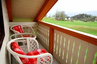 a balcony with red and white chairs and a window at Apartma Eržen in Zgornje Gorje