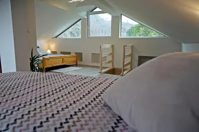 a bedroom with a bed and a desk and windows at Apartma Eržen in Zgornje Gorje