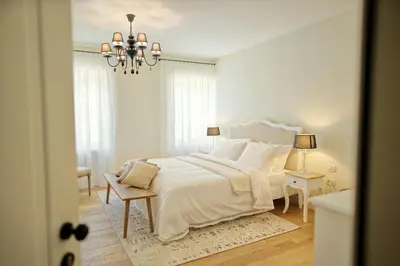 a white bedroom with a large bed and a chandelier at Villa Majda in Osp
