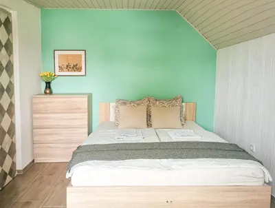 a bedroom with a large bed with a blue wall at Deerwood Villa-Modern cozy 2br apartment with castle view in Bled